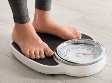 A woman weighs herself on a scale