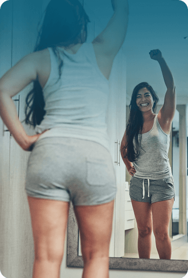 A woman looks in the mirror, feeling happy with her body
